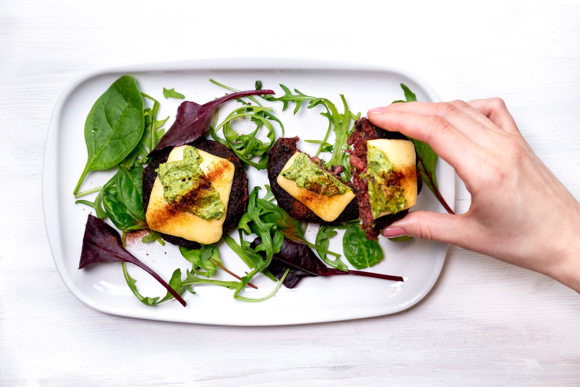 Hands garnishing a dish with microgreens